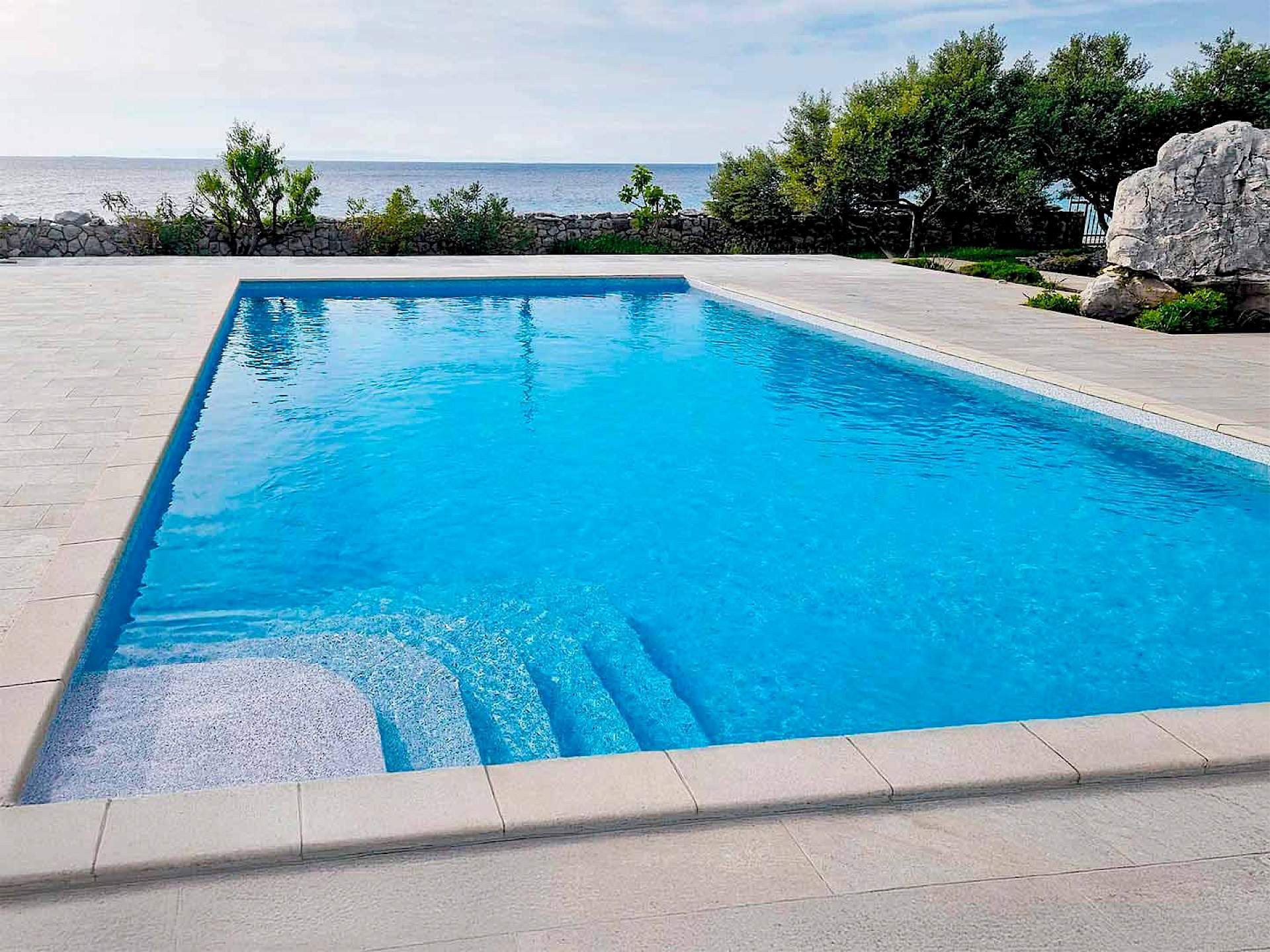 vanjski bazen sa stepenicama i svijetlom folijom uz more, besprijekorno čist zahvaljujući vrhunskoj dodatnoj opremi