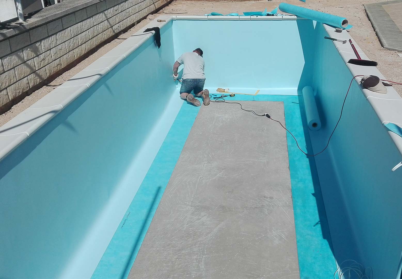 Stručno postavljanje plave bazenske folije u unutrašnjost bazena u izgradnji