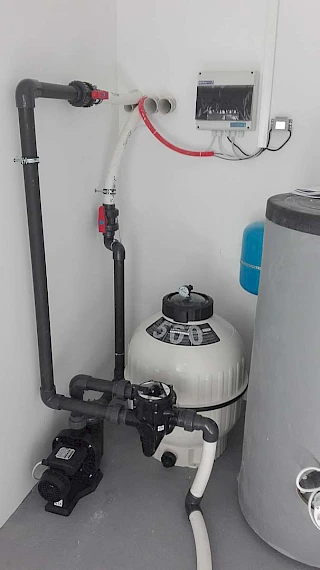 Precizno spojen bijeli pješčani filter za bazen s višeputnim ventilom i sivim PVC cijevima u urednoj strojarnici