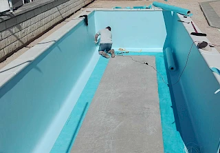 Majstor precizno vari svijetlo plavu armiranu bazensku foliju unutar betonske školjke bazena