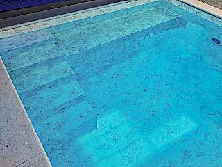 Detalj napunjenog bazena sa stepenicama na kojima se ističe ugrađena armirana bazenska folija s plavim efektom mramora