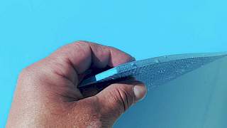 Krupni kadar muške ruke koja izbliza pokazuje teksturu i debljinu uzorka plave armirane bazenske folije na svjetlu