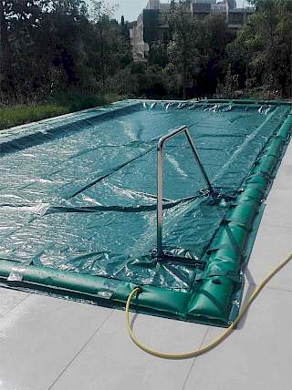 Vanjski bazen sa stepenicama, potpuno zaštićen čvrstim zelenim zimskim bazenskim prekrivačem za sigurno zazimljavanje