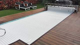 Luksuzni vanjski bazen s drvenom terasom, ležaljkama i ugrađenim automatskim lamelarnim prekrivačem (roletom) za bazen.