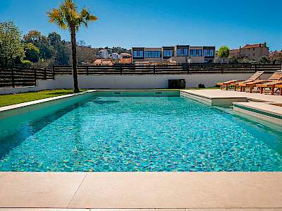 Vanjski bazen s kamenim opločenjem i pogledom na vile u Istri