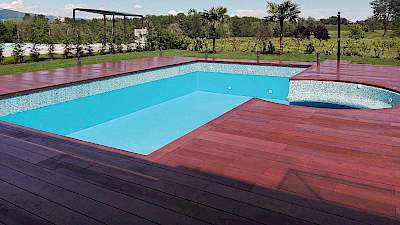 Bazen s drvenim deckingom, mozaik detaljima i tirkiznom vodom u privatnom dvorištu s palmama u Zagrebu